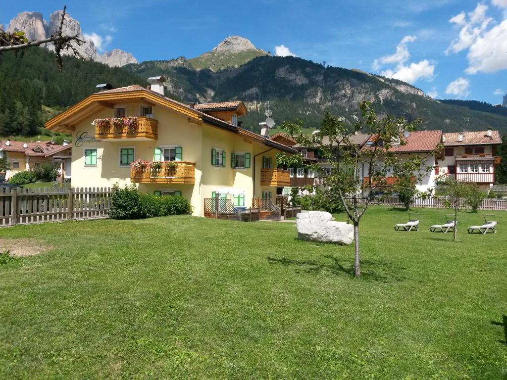 a house with a yard with a mountain in the background at Residence Ercabuan in Campitello di Fassa