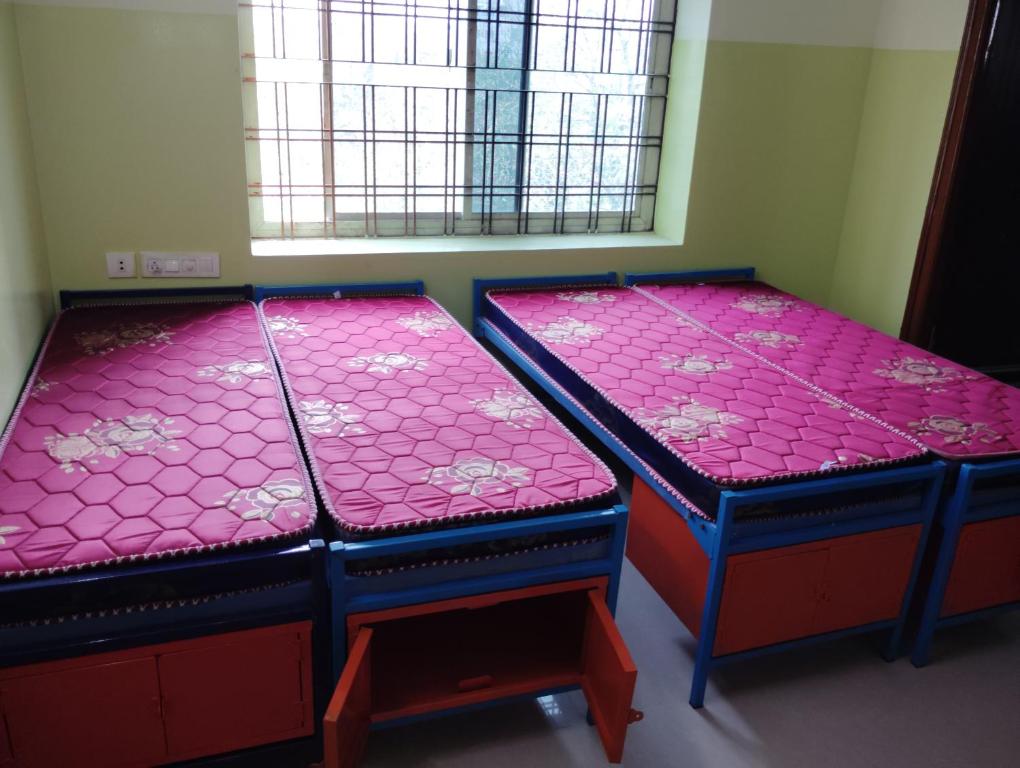 2 letti in una camera con lenzuola rosa di SHRII SAI LIKITHA BOY'S HOSTEL a Hyderabad