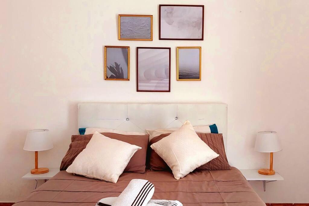 a bedroom with a bed with four pictures on the wall at Pet friendly T1 sossegado c/ pátio espaçoso in Luanda