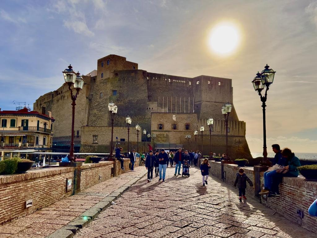 un grupo de personas caminando frente a un castillo en Palazzo Chiatamone, en Nápoles