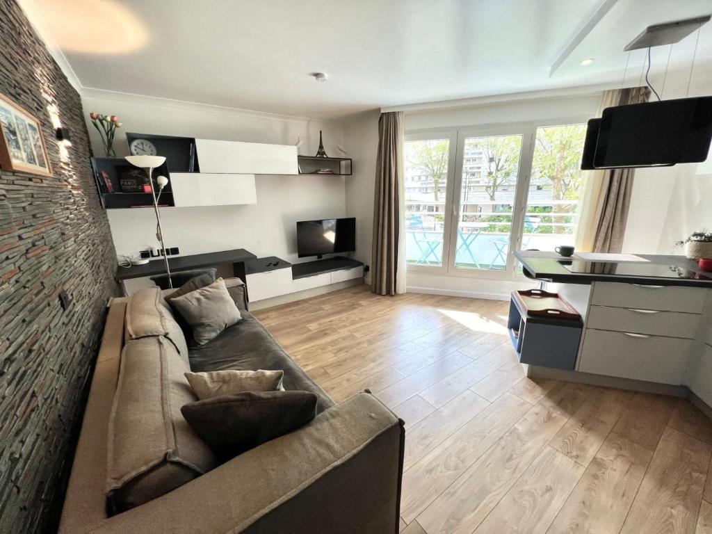 un salon avec un canapé, une table et une télévision dans l'établissement Cosy 1BR Apt in Modern Residence Paris La Défense, à Courbevoie