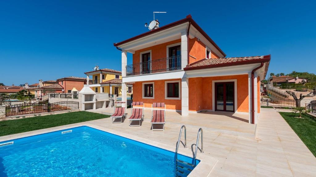 a villa with a swimming pool in front of a house at Villa Nia with Private Pool in Karigador
