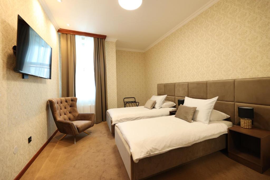 una habitación de hotel con 2 camas y una silla en Hotel Vidović, en Banja Luka