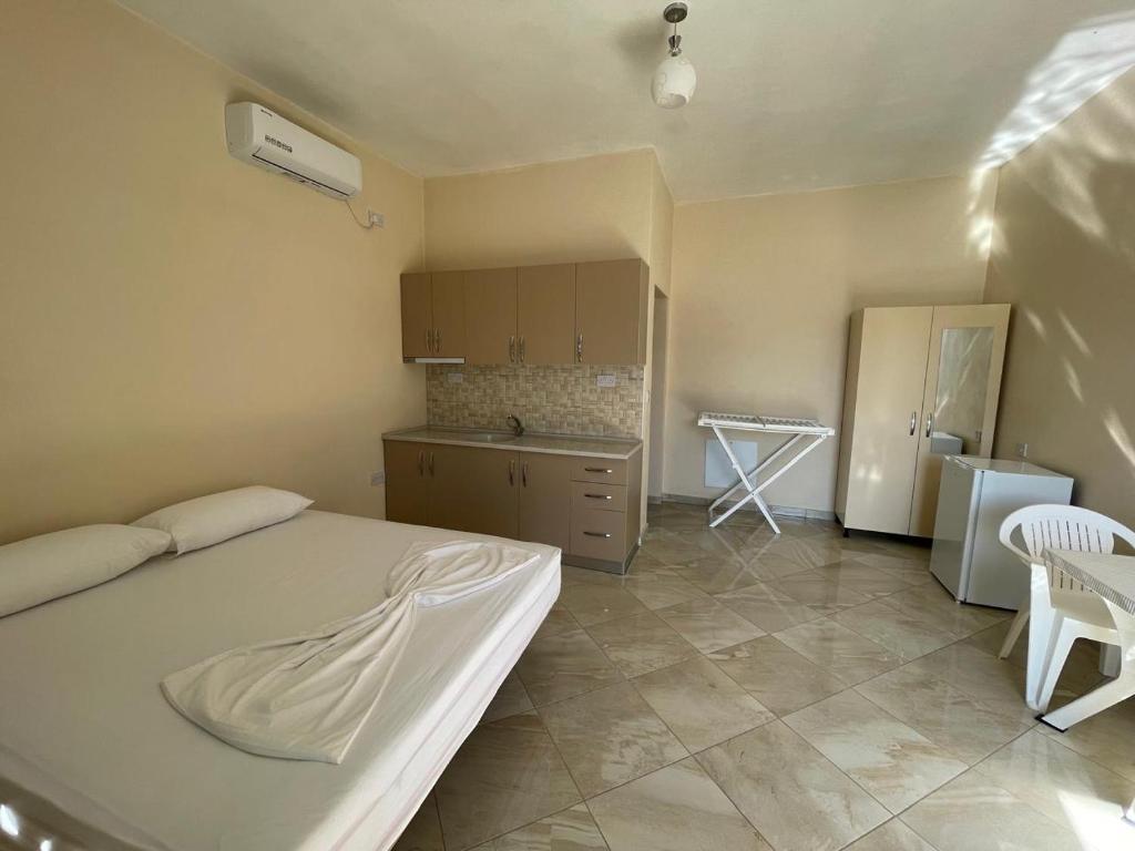 a bedroom with a white bed and a kitchen at Lumaj Hostel in Shkodër