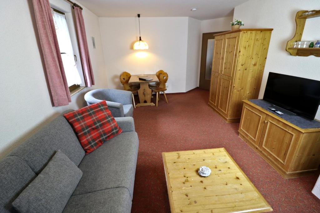 Una sala de estar con un sofá, un televisor y una mesa. en Apartment 12 - Ferienresidenz Roseneck, 2 Schlafzimmer, mit Schwimmbad in Todtnauberg bei Feldberg, en Todtnauberg