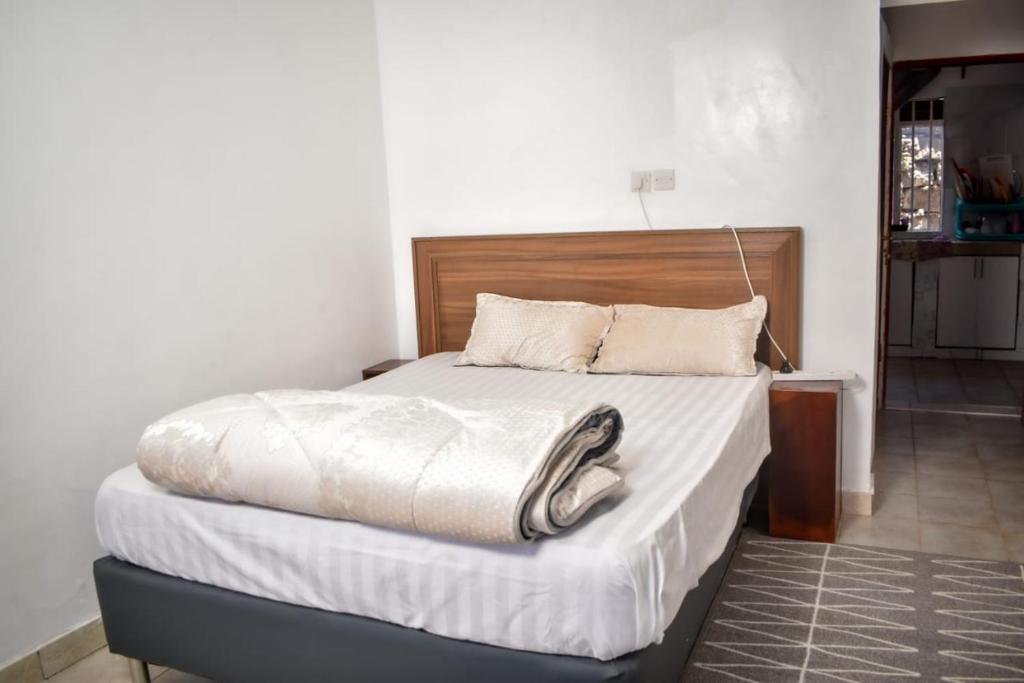 KiambuにあるMella Homes Limuruのベッドルーム1室(大型ベッド1台、木製ヘッドボード付)