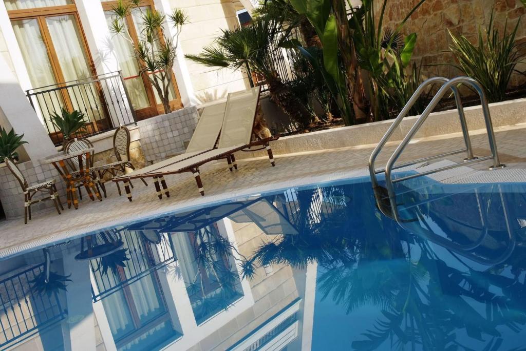 - une piscine avec 2 chaises à côté d'un bâtiment dans l'établissement UNICO Albatres Palace Salento by Life Resorts, à San Vito dei Normanni