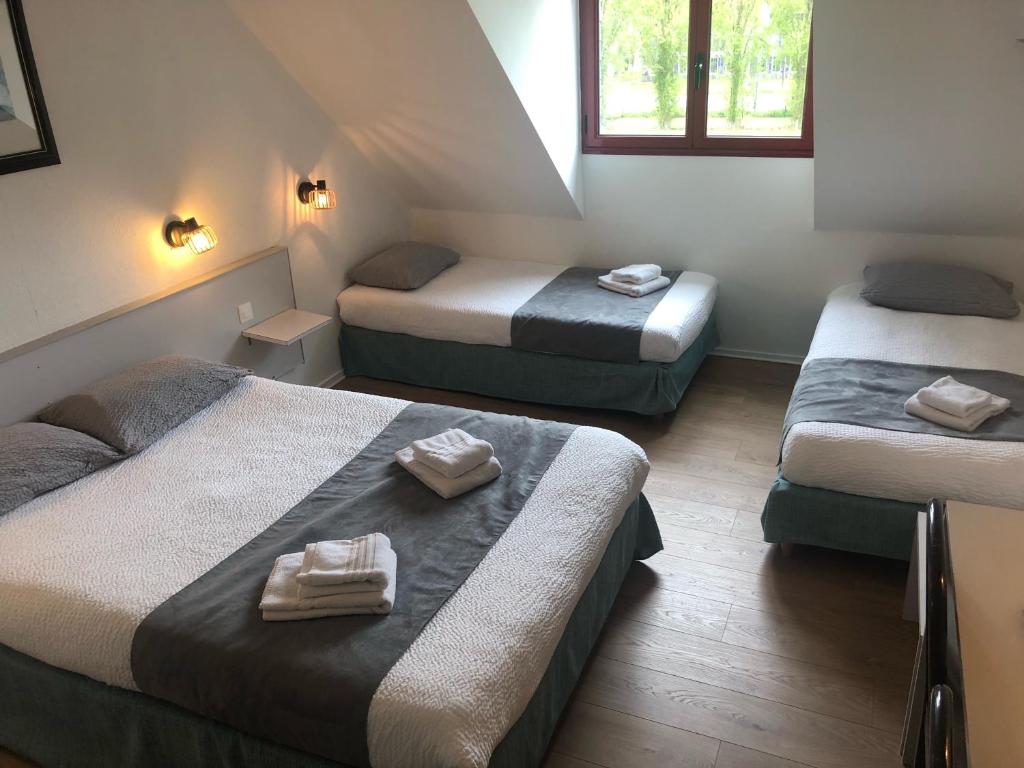a room with three beds with towels on them at Logis Hôtel Lucotel in Lanvollon