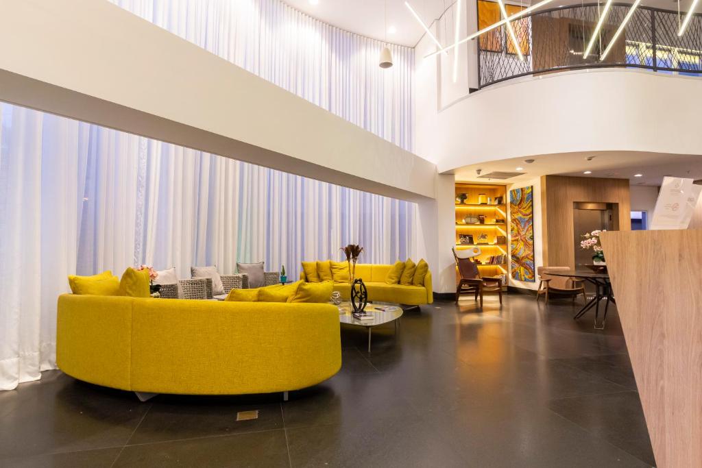 ein Wohnzimmer mit gelben Sofas und Stühlen in der Unterkunft Hotel Cassino Tower São José do Rio Preto by Nacional Inn in Sao Jose do Rio Preto