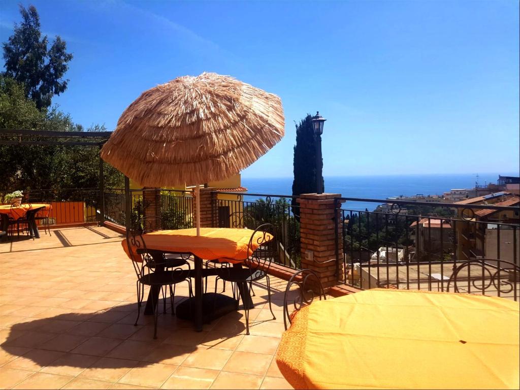 a patio with a table and a straw umbrella at Le Grand Soleil Apartments in Taormina