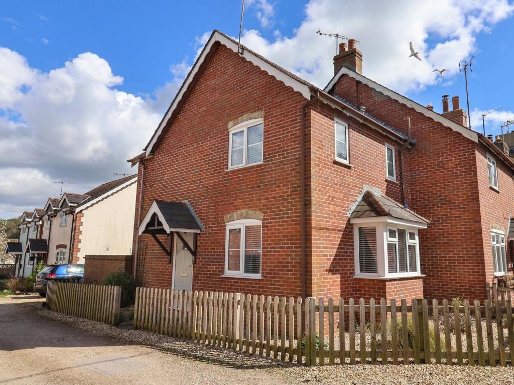 una casa de ladrillo con una valla delante en 8 Biddlecombe Orchard, en Bridport