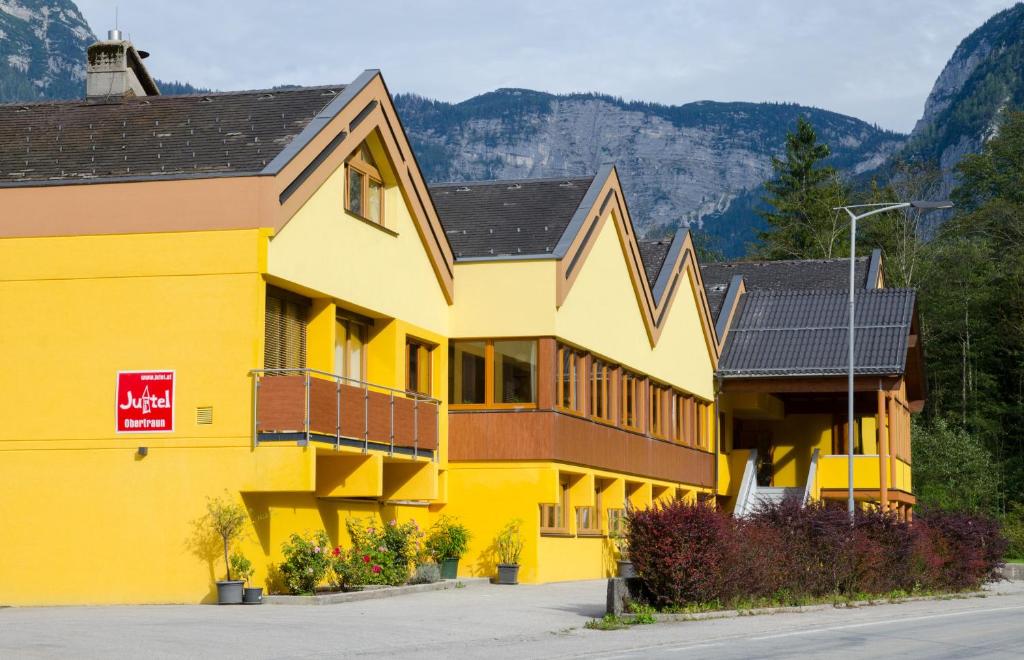 een geel gebouw met bergen op de achtergrond bij Jutel Obertraun in Obertraun