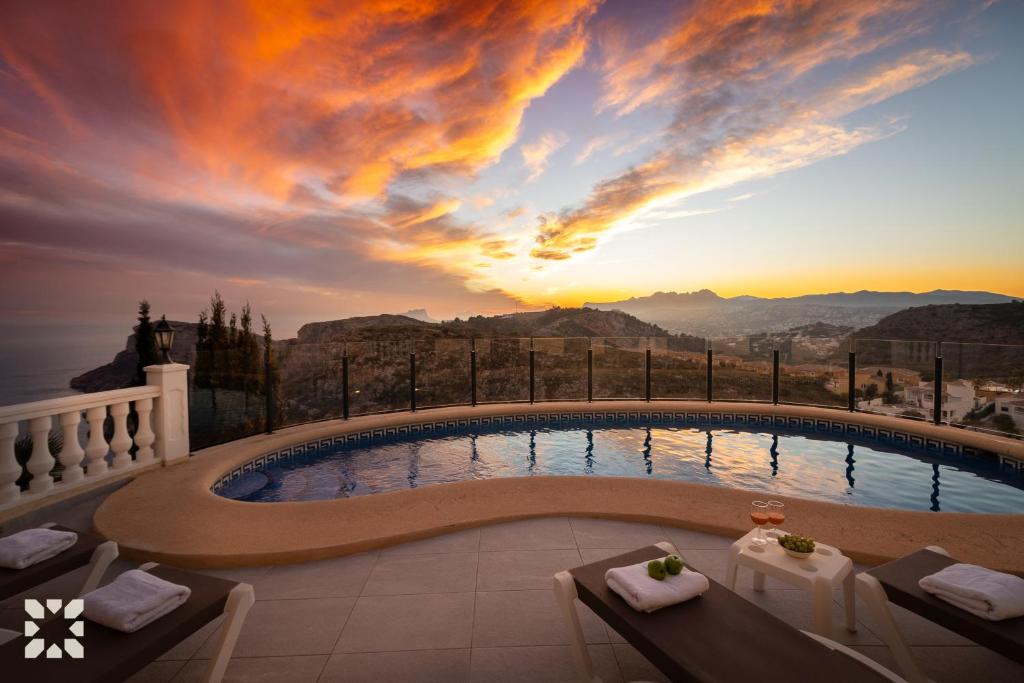 einen Pool mit Sonnenuntergang im Hintergrund in der Unterkunft Villa Sunset Rock by Abahana Villas in Benitatxell