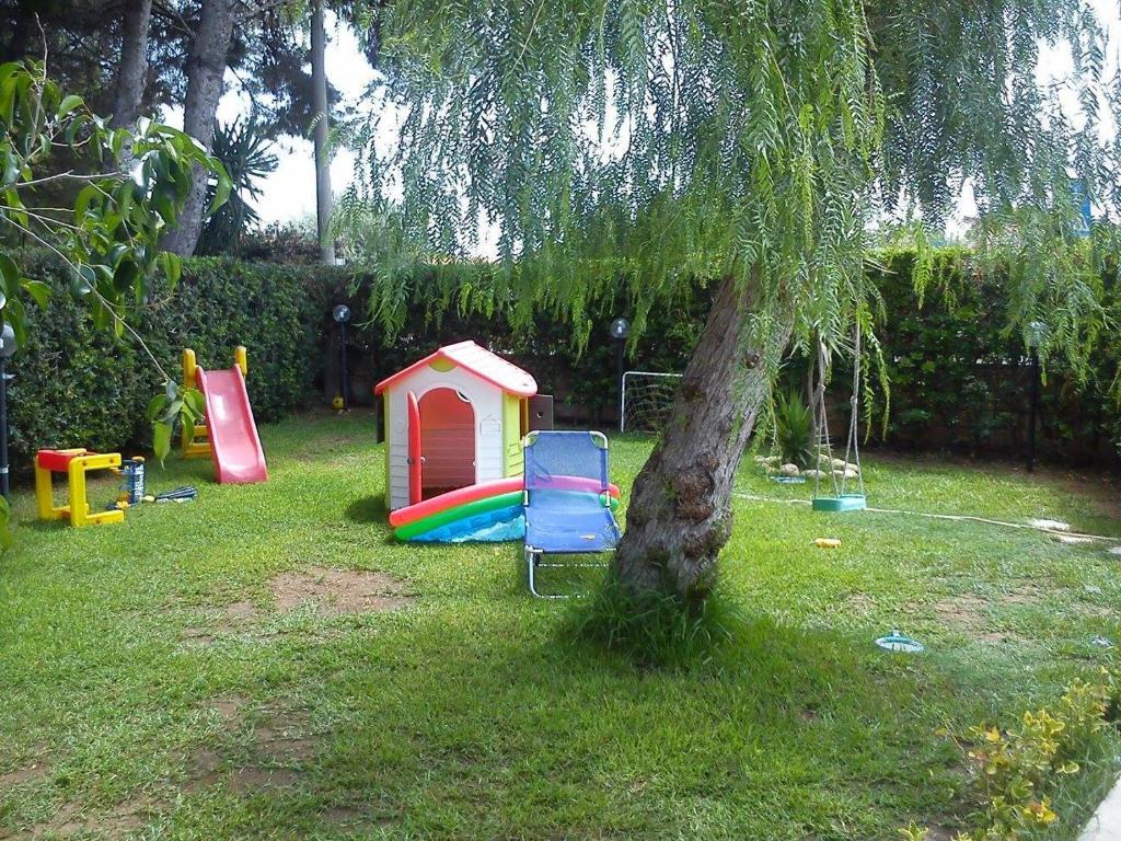 un patio trasero con una casa de juegos y un árbol en Casa Vacanza Dei Lidi, en Fontane Bianche