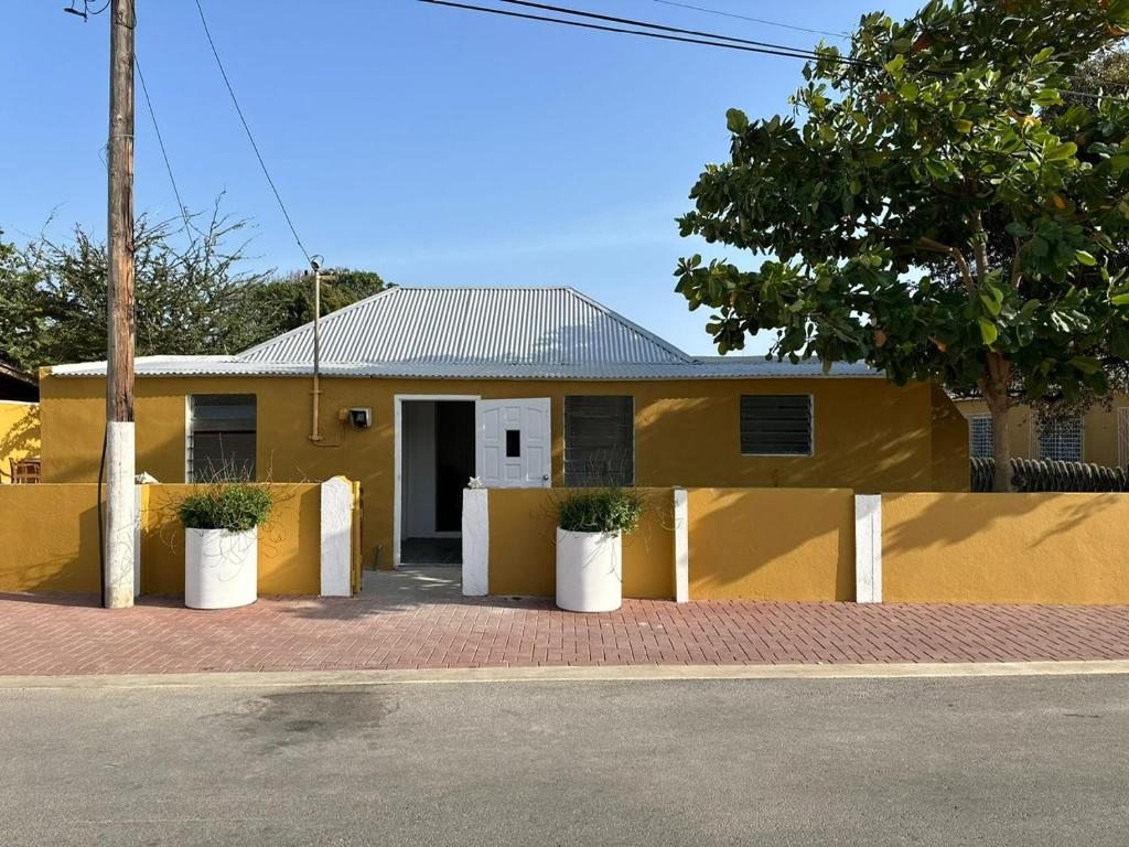 uma casa amarela com dois vasos de plantas em frente em Casita de Rincon 1 em Hato