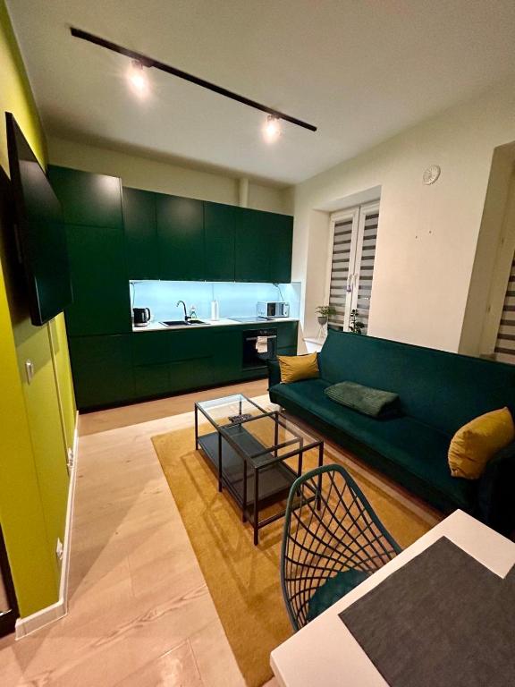 a living room with a green couch and a kitchen at Apartment Targowa L7 in Lublin