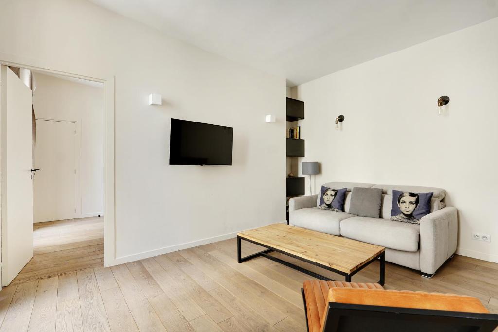 un salon blanc avec un canapé et une table dans l'établissement Pick A Flat's Apartment in Le Marais - Rue Sainte Croix de la Bretonnerie, à Paris