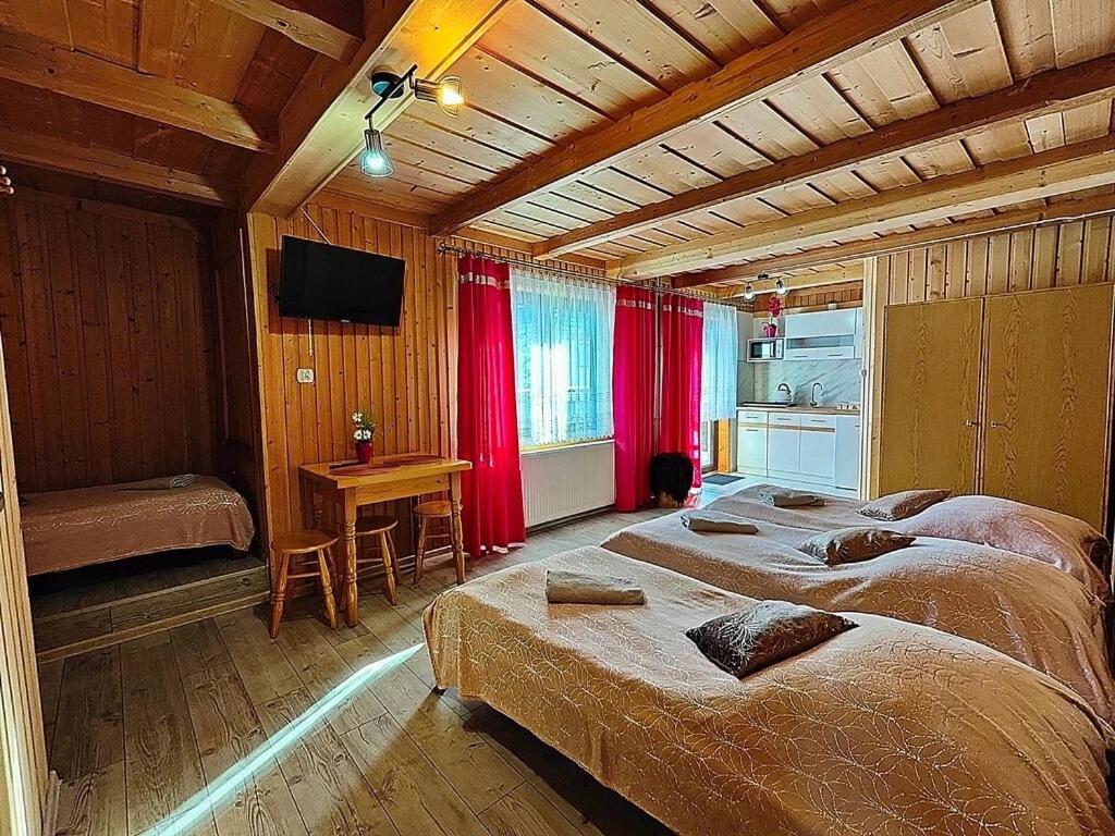 1 dormitorio con 2 camas, mesa y TV en Sichlański Zakątek, en Murzasichle