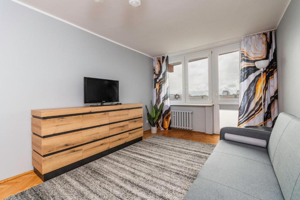a living room with a tv and a dresser with a tv at Fala 2 by Grand Apartments in Gdańsk