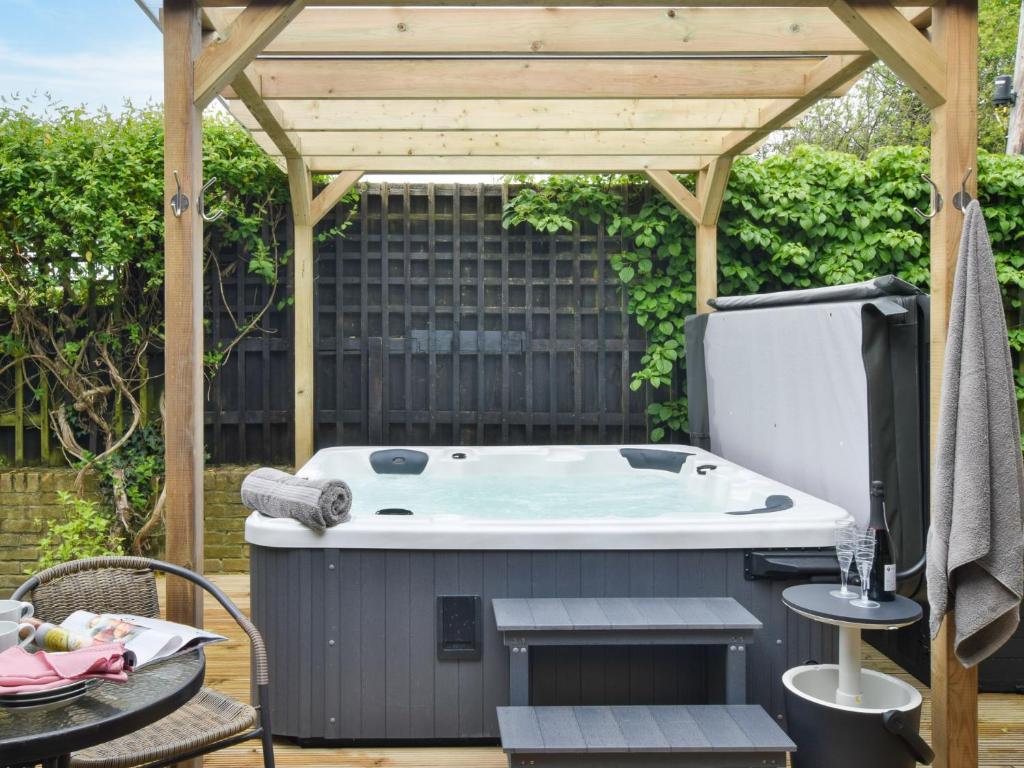 een hot tub op een patio met een houten pergola bij 4 Bed in Ashford 86647 in Ashford