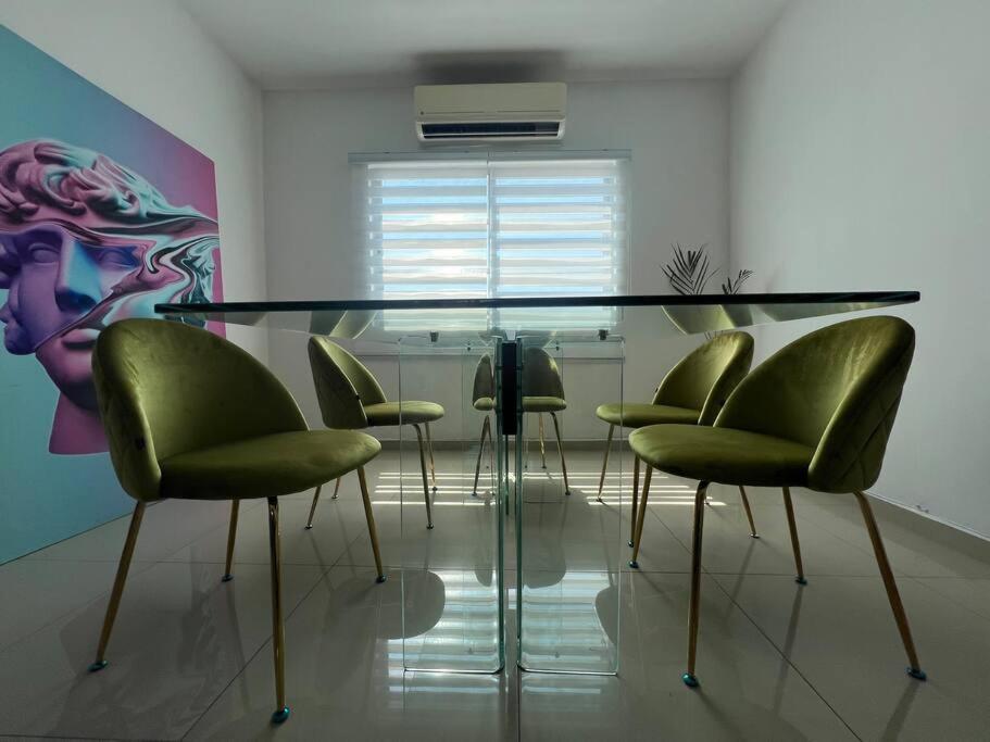 a dining room with a glass table and green chairs at Departamento Torres Mina Residencial in Villahermosa