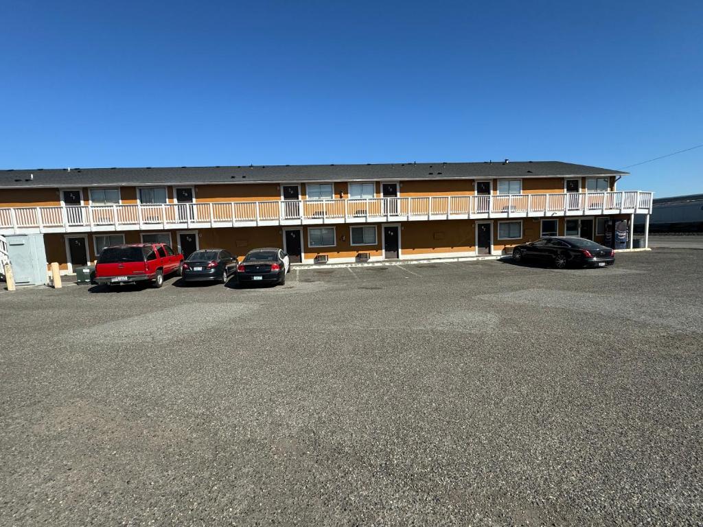 a large building with cars parked in a parking lot at Airport Motel in Pasco