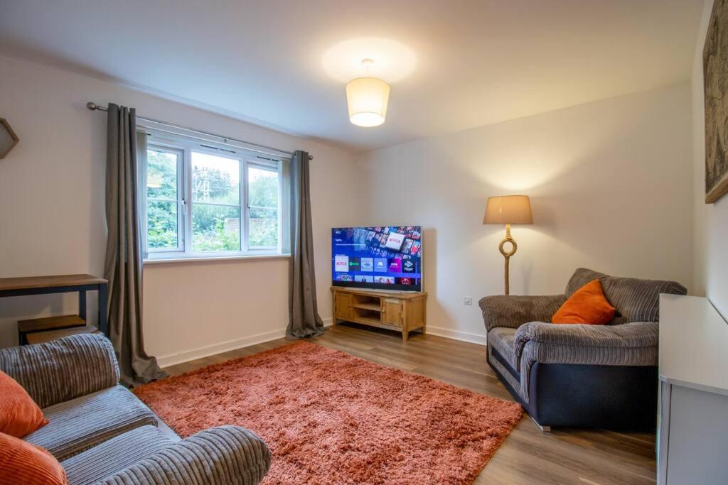 sala de estar con 2 sofás y TV de pantalla plana en 2 bed flat near airport &parking, en Paisley