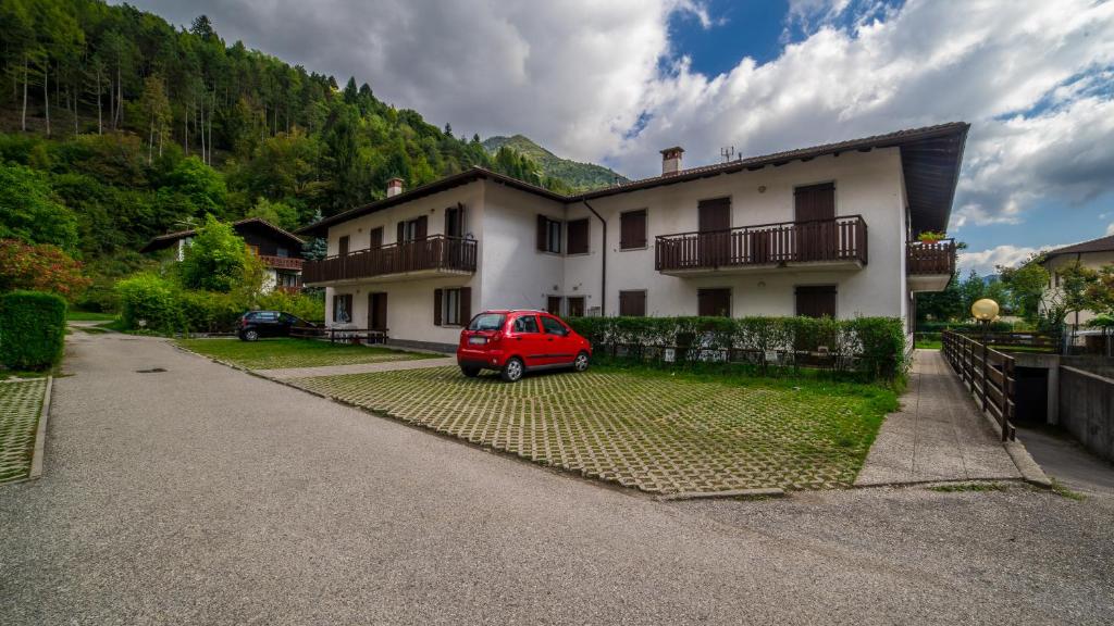 une camionnette rouge garée devant une maison dans l'établissement Residence Fiore, à Ledro