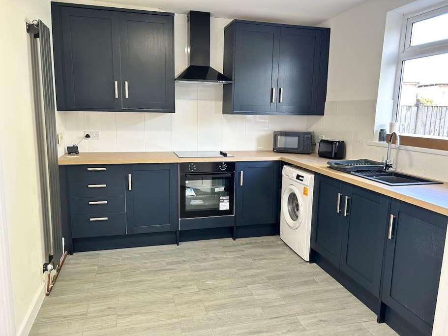 a kitchen with blue cabinets and a washing machine at Montrose House 3 bedroom home with Parking in Frodingham
