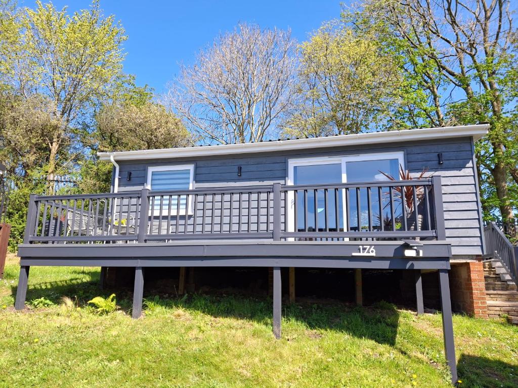 a blue tiny house with a large deck at Chalet 176 Glan Gwna Park Caernarfon in Caeathro