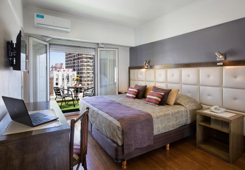 een slaapkamer met een bed en een bureau met een laptop bij Hotel Impala in Buenos Aires