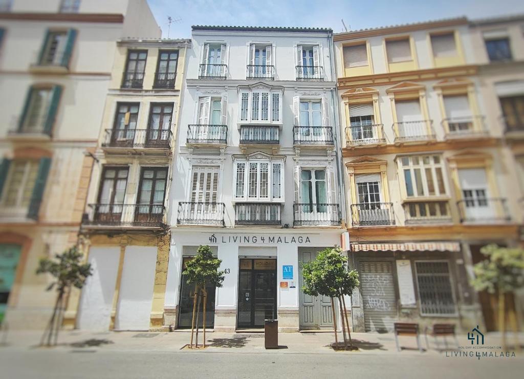 un gran edificio blanco en una calle de la ciudad en Living4Malaga Suites Superior, en Málaga