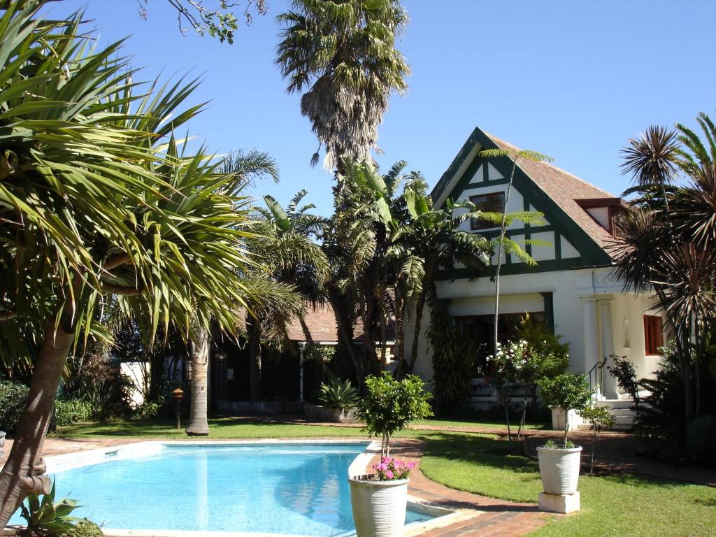 ein Haus mit einem Pool und Palmen in der Unterkunft King George's Guest House in Port Elizabeth