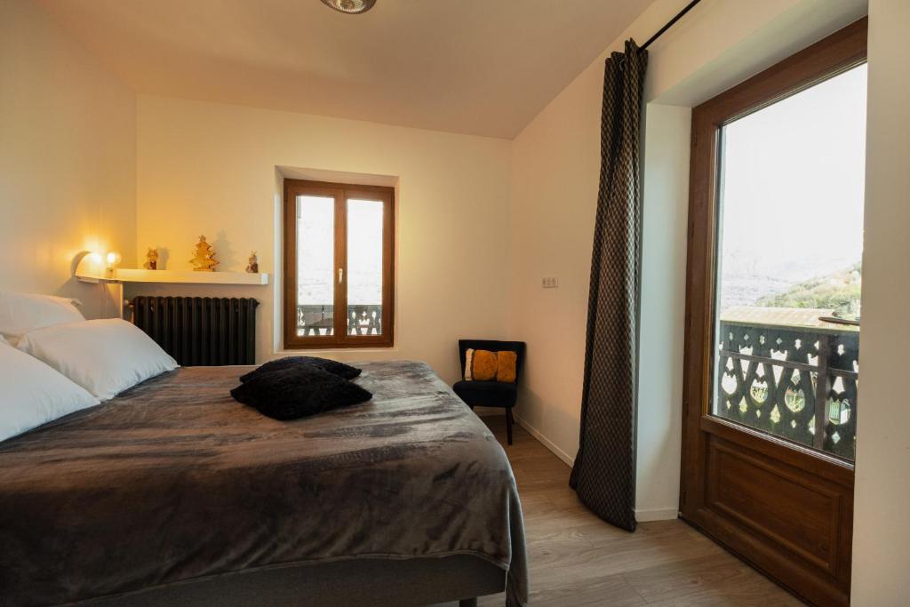 um quarto com uma cama e uma grande janela em Chalet les Myrtilles em Venthon