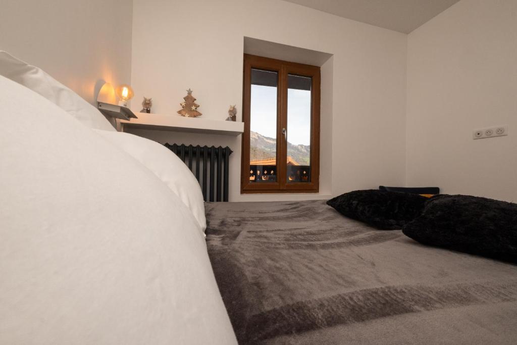 una camera bianca con un letto e una finestra di Chalet les Myrtilles a Venthon