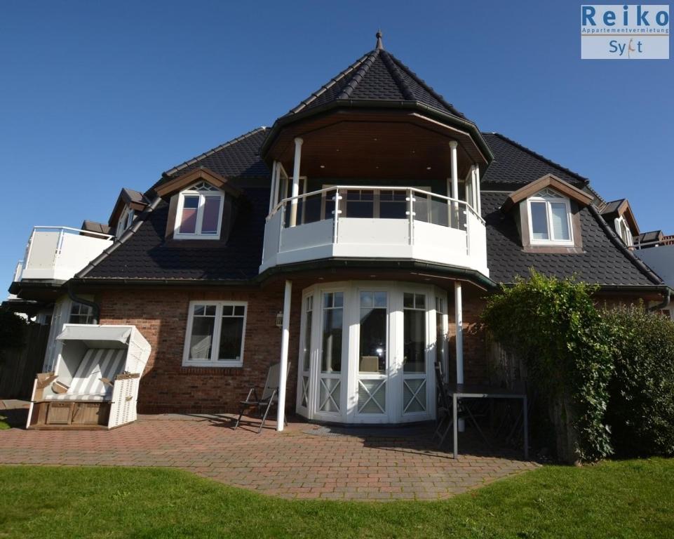 een huis met een witte veranda en een dak bij Syltrose Whg 2 in Westerland