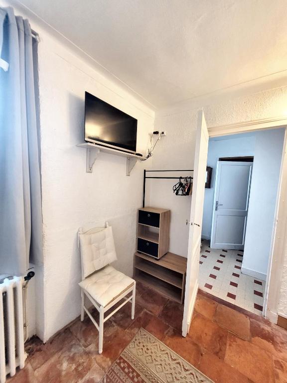 a living room with a chair and a tv on the wall at Studio avec jardin clos et wifi a Langon in Langon