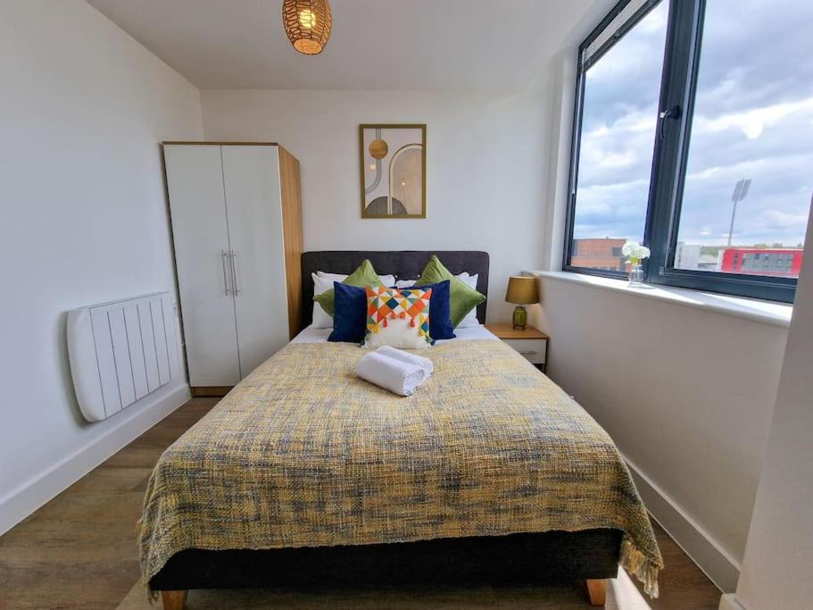 a bedroom with a bed and a large window at Stunning Old Trafford Apartment in Manchester