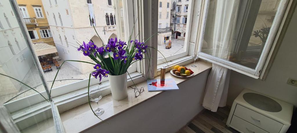 a vase of purple flowers on a window sill at Old Square view apartment in Split