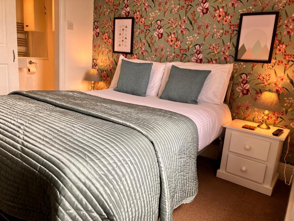 a bedroom with a large bed with floral wallpaper at Laurel Bank House in Penrith