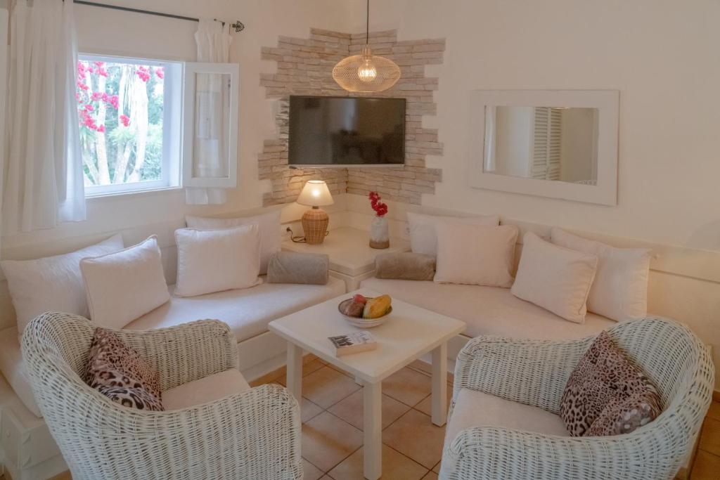 sala de estar con sofá, sillas y mesa en Bungalows Casa Amarilla, en Playa de Migjorn