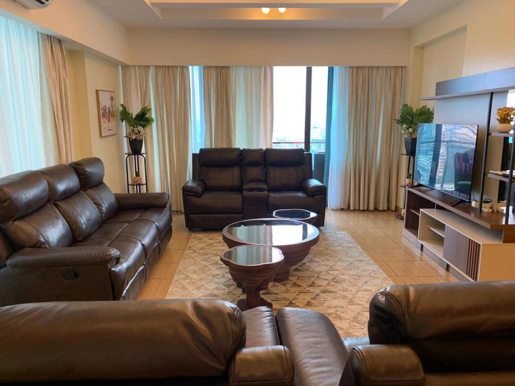 uma sala de estar com mobiliário de couro e uma televisão de ecrã plano em Kitengule Apartment 001 em Dar es Salaam