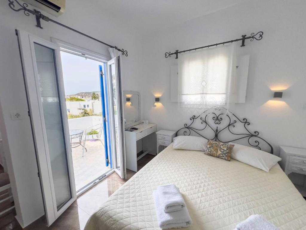a white bedroom with a bed and a balcony at Pension Barbara in Katapola