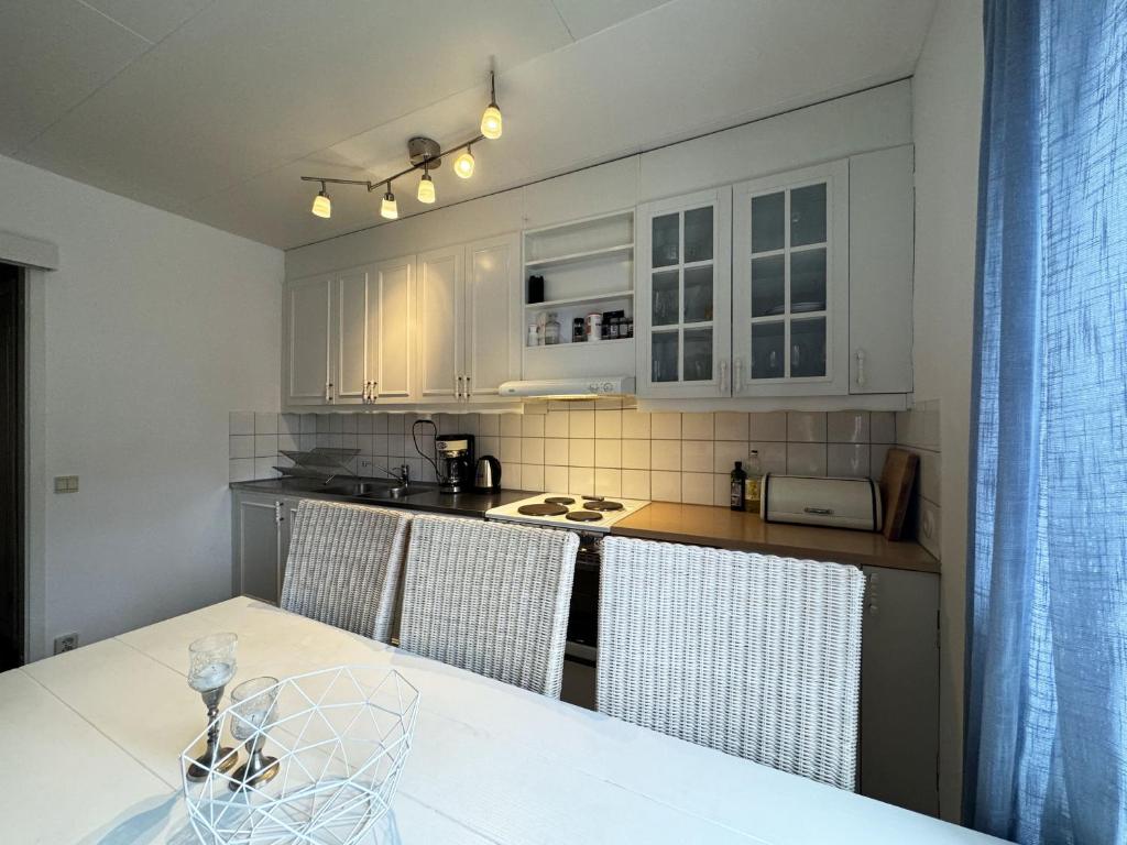 una cocina con armarios blancos y una mesa con sillas. en Nice, quiet apartment in central Karlstad, en Karlstad