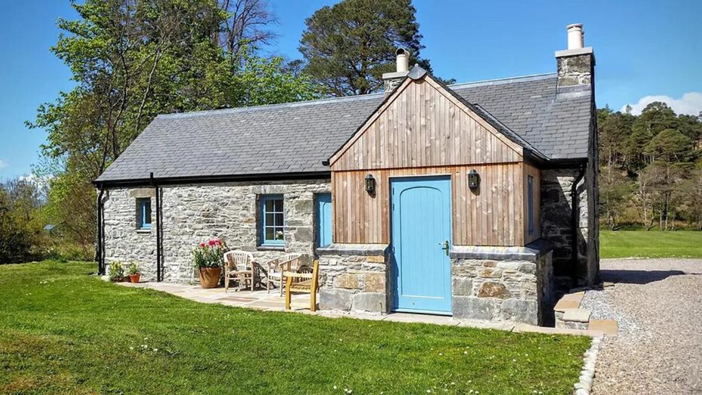 a stone cottage with a blue door in a yard at The Smiddy in Lochailort