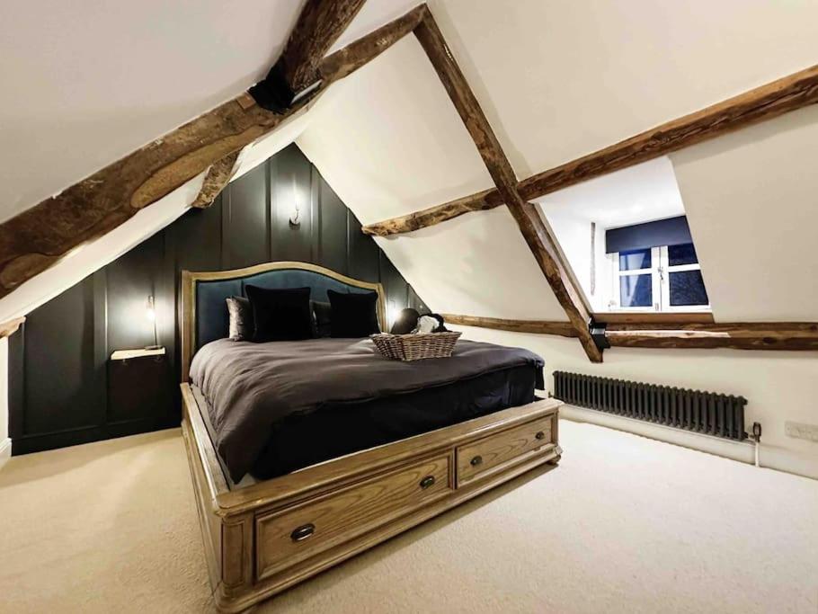 - une chambre mansardée avec un grand lit dans l'établissement Cotswold Garden Cottage, à Chipping Norton