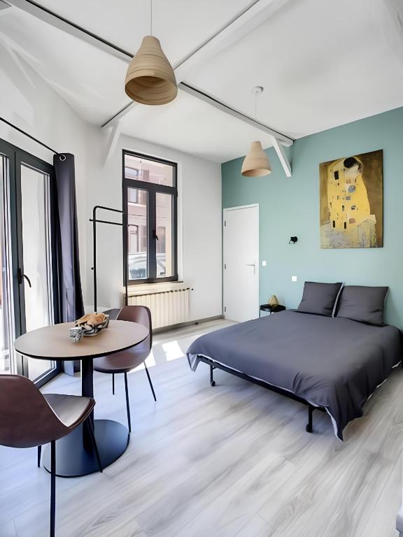 une chambre avec un lit et une table dans l'établissement La Licorne, grand studio chaleureux, à Amiens