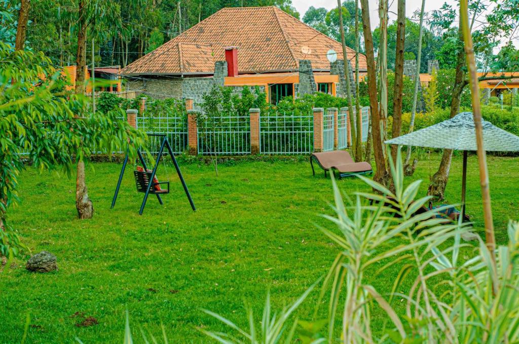 a yard with a swing set in the grass at Karisimbi Cave Resort in Ruhengeri