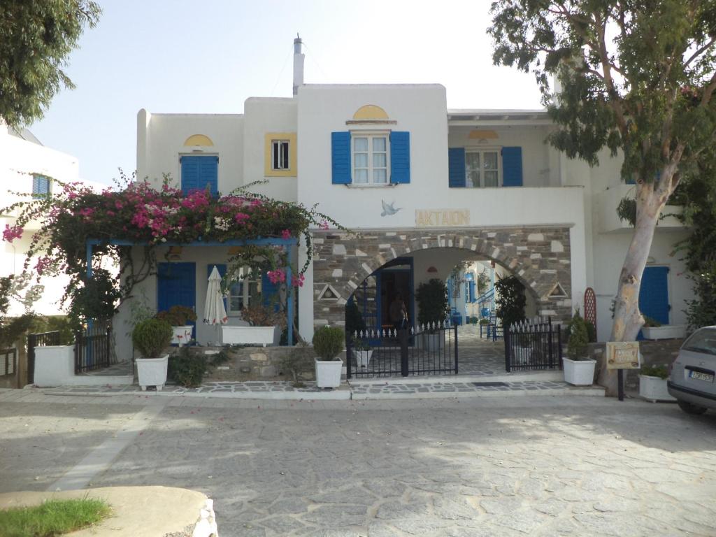 a white building with blue shutters and a gate at Akteon Hotel in Logaras
