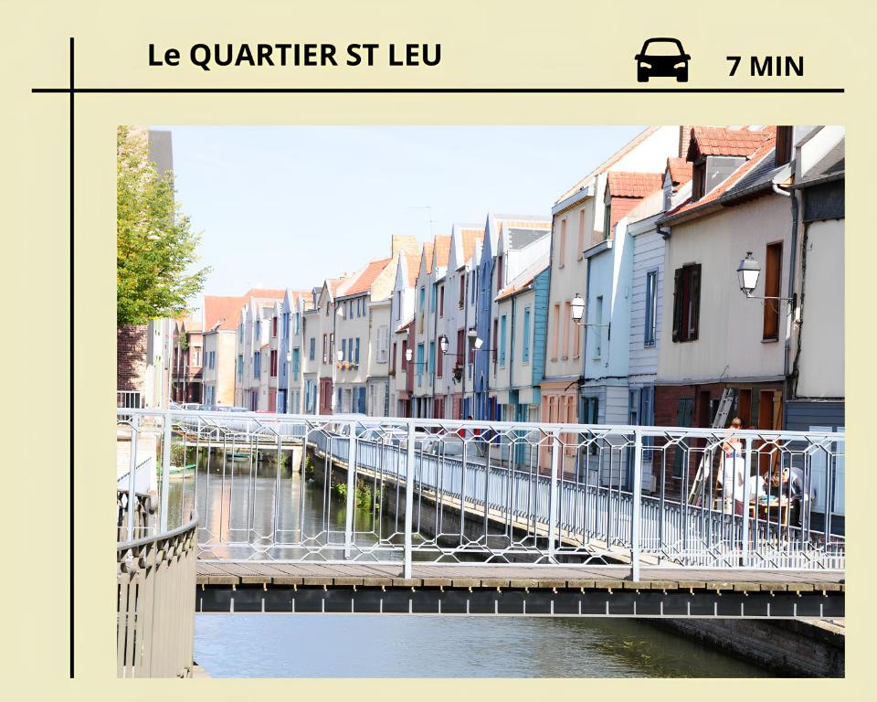 un ponte su un fiume in una città con edifici di La Licorne, grand studio chaleureux ad Amiens